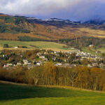 LOOKING ACROSS COUNTRYSIDE TO THE TOWN OF PITLOCHRY, A POPULAR RESORT NORTH WEST OF DUNKELD, WITH THE SNOW COVERED HILLS BEYOND, PERTH & KINROSS